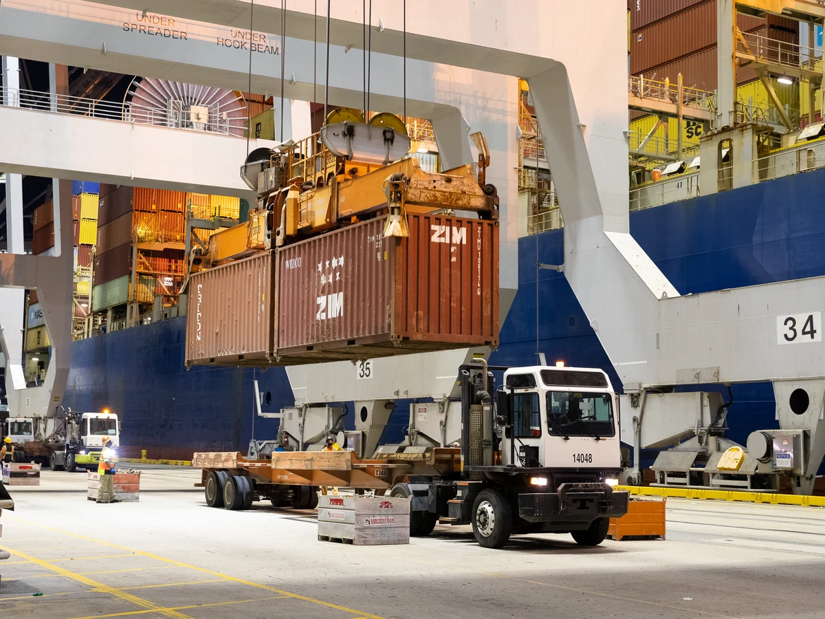 Container cranes lifting cargo from a ship at the Port of Savannah during evening light.