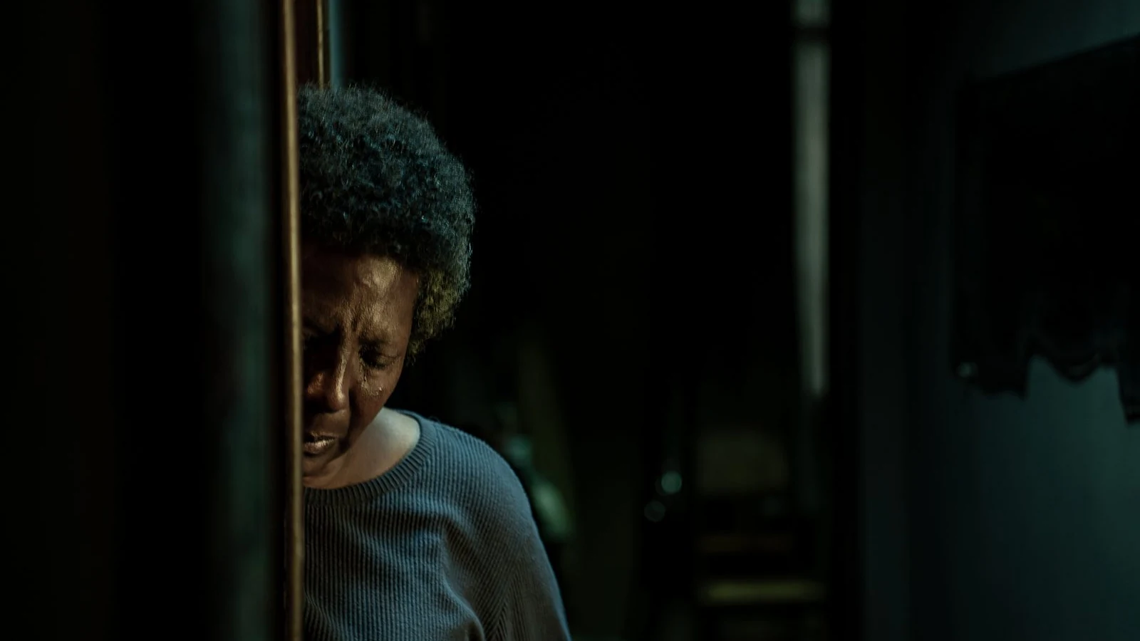 A woman stands in a dim interior in an official image published by Netflix.