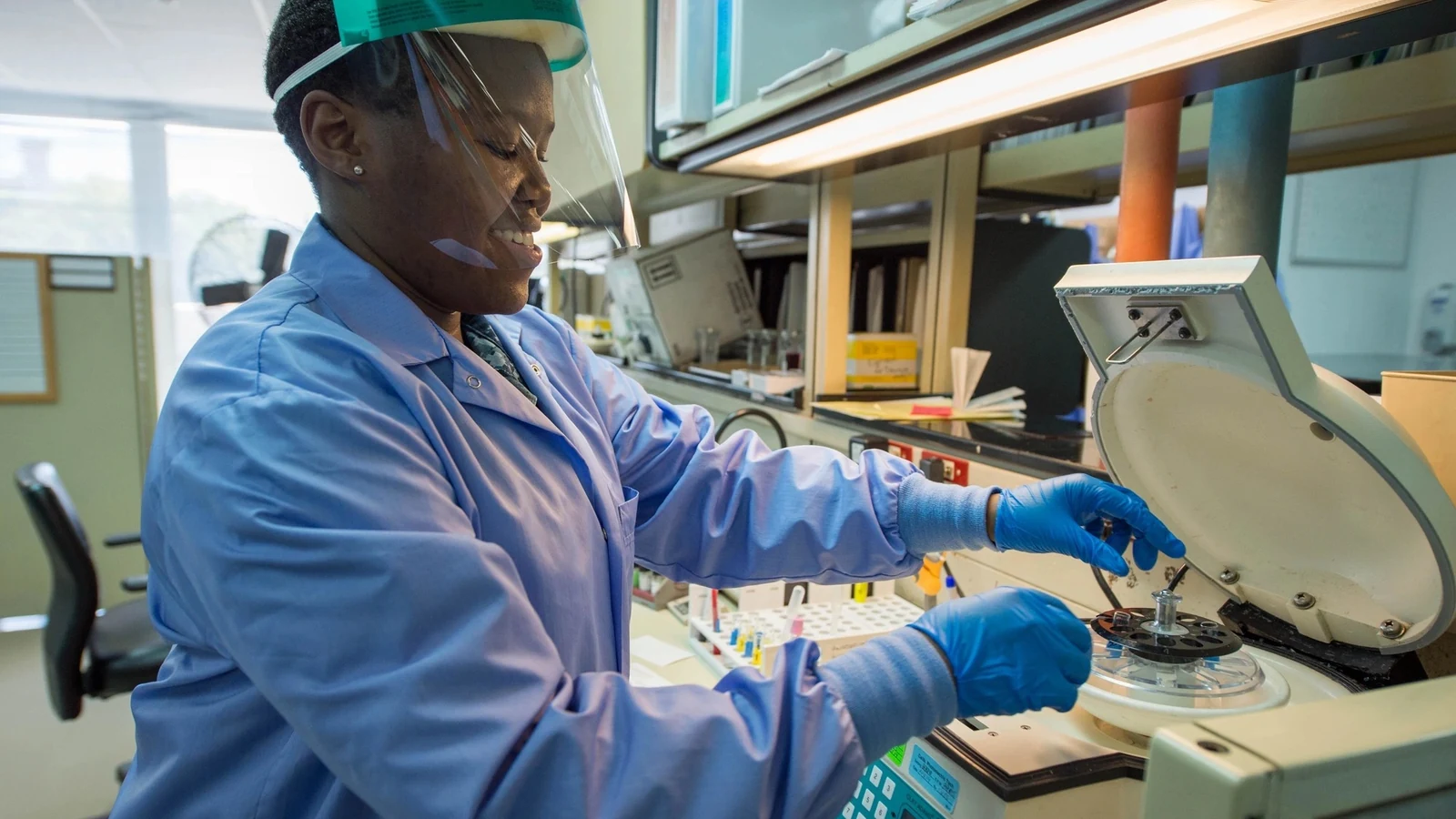 A medical laboratory technician loads blood-sample tubes into a centrifuge.