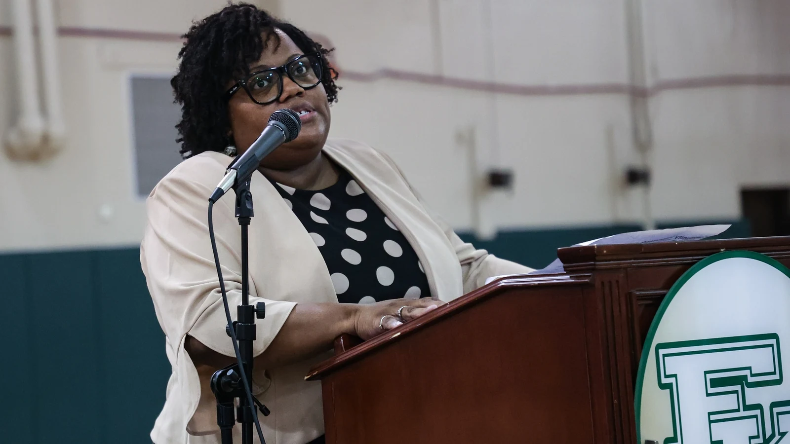 A school superintendent speaks at a lectern during a back-to-school staff rally.