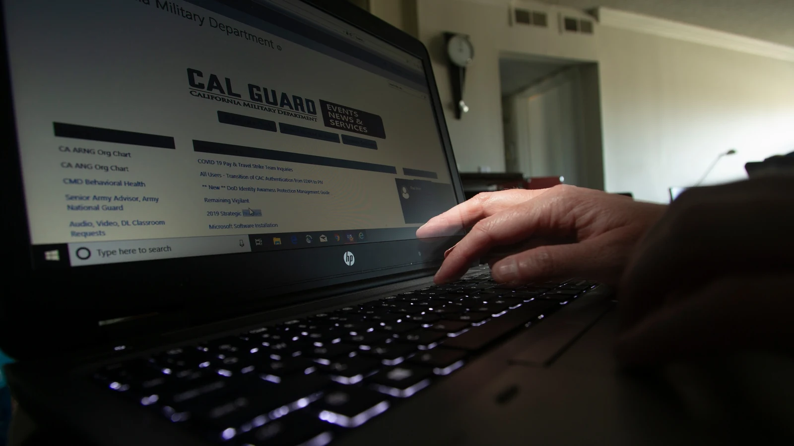 A person works on a laptop from a home table, with one hand on the keyboard.