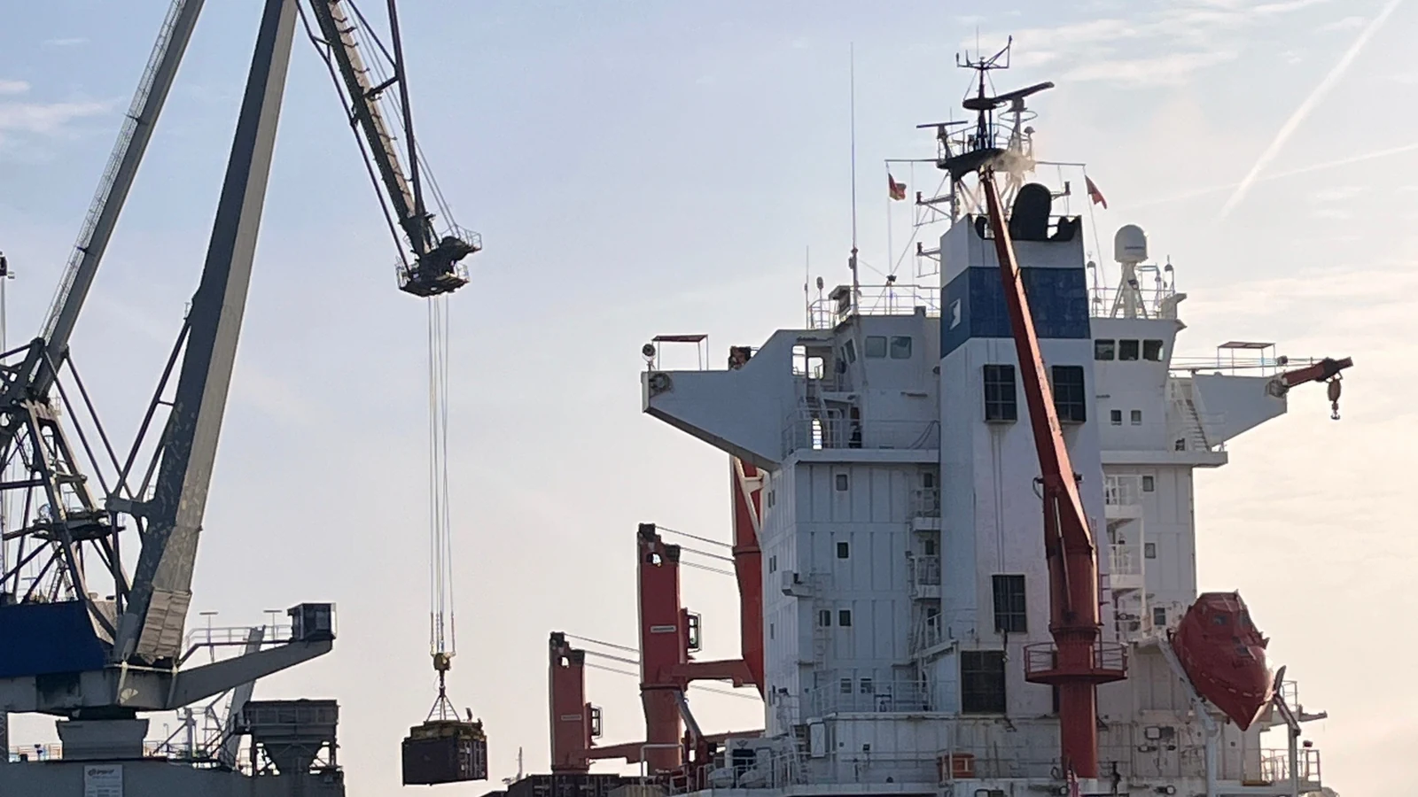 A container ship sits alongside cranes at a German port.