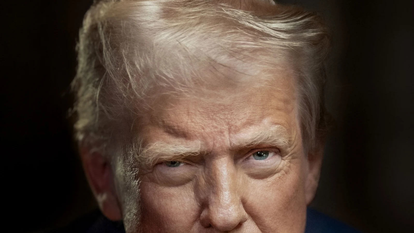Official White House portrait of President Donald Trump in a dark suit with an American flag behind him.