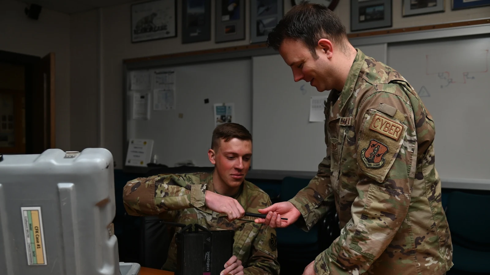 Two Air National Guard cybersecurity specialists inspect radio communications equipment.