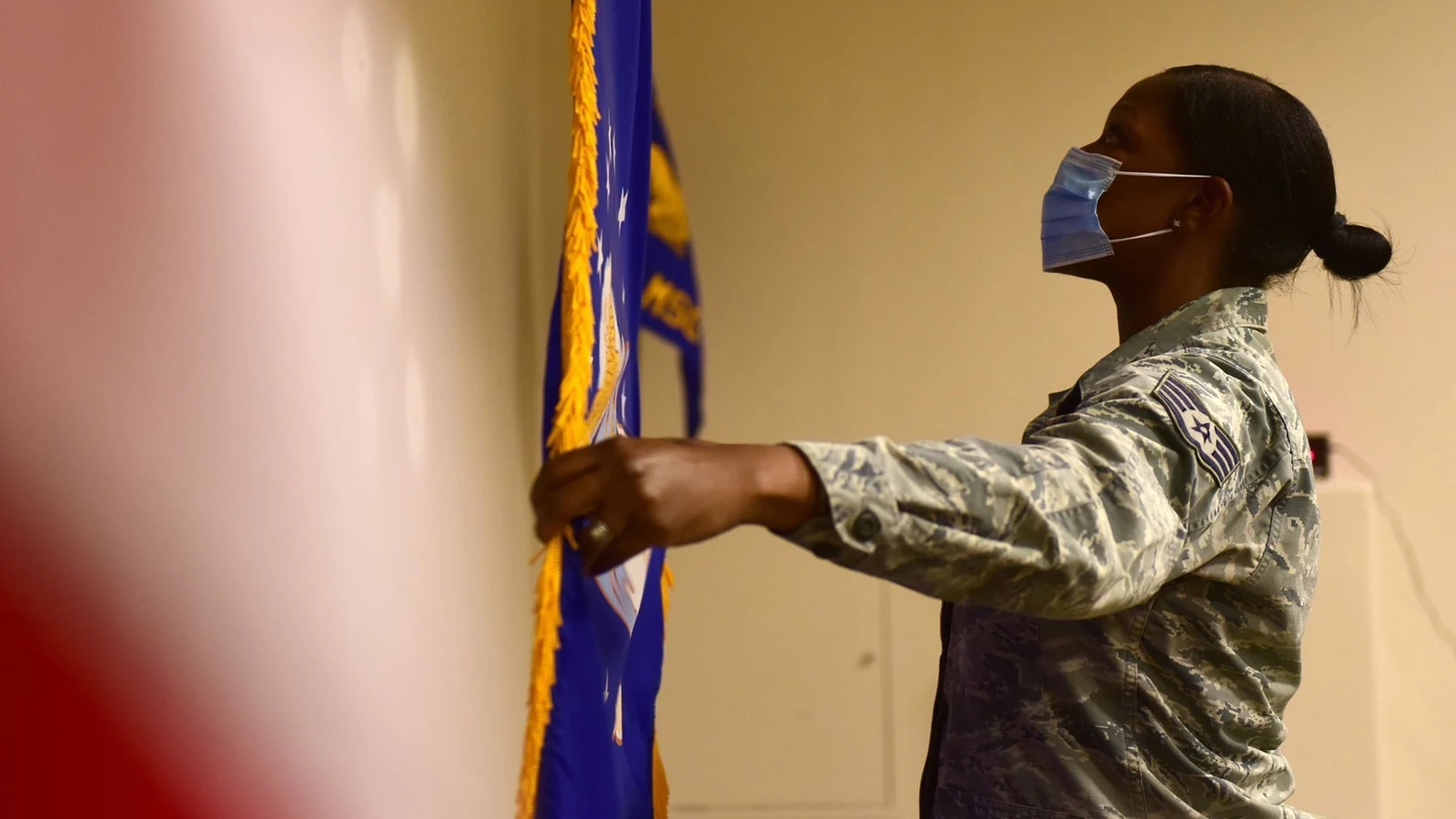 A legal staff member positions the Air Force flag in a courtroom before it opens.
