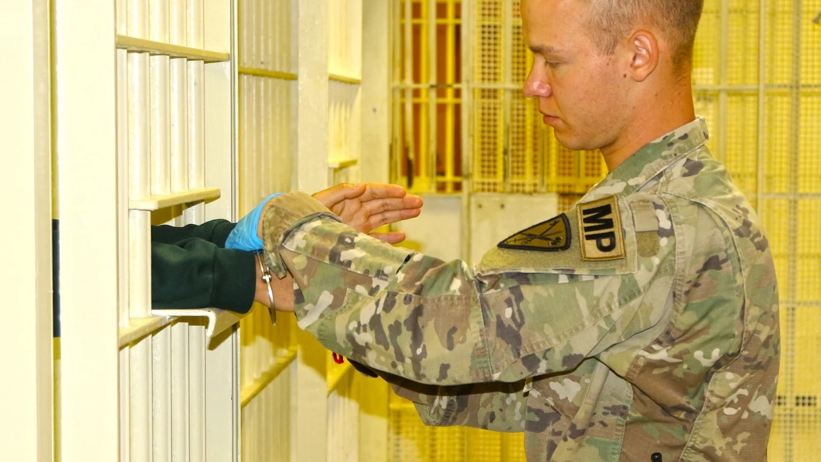 A uniformed correctional specialist reviews safety procedures with a prisoner inside a military correctional facility.