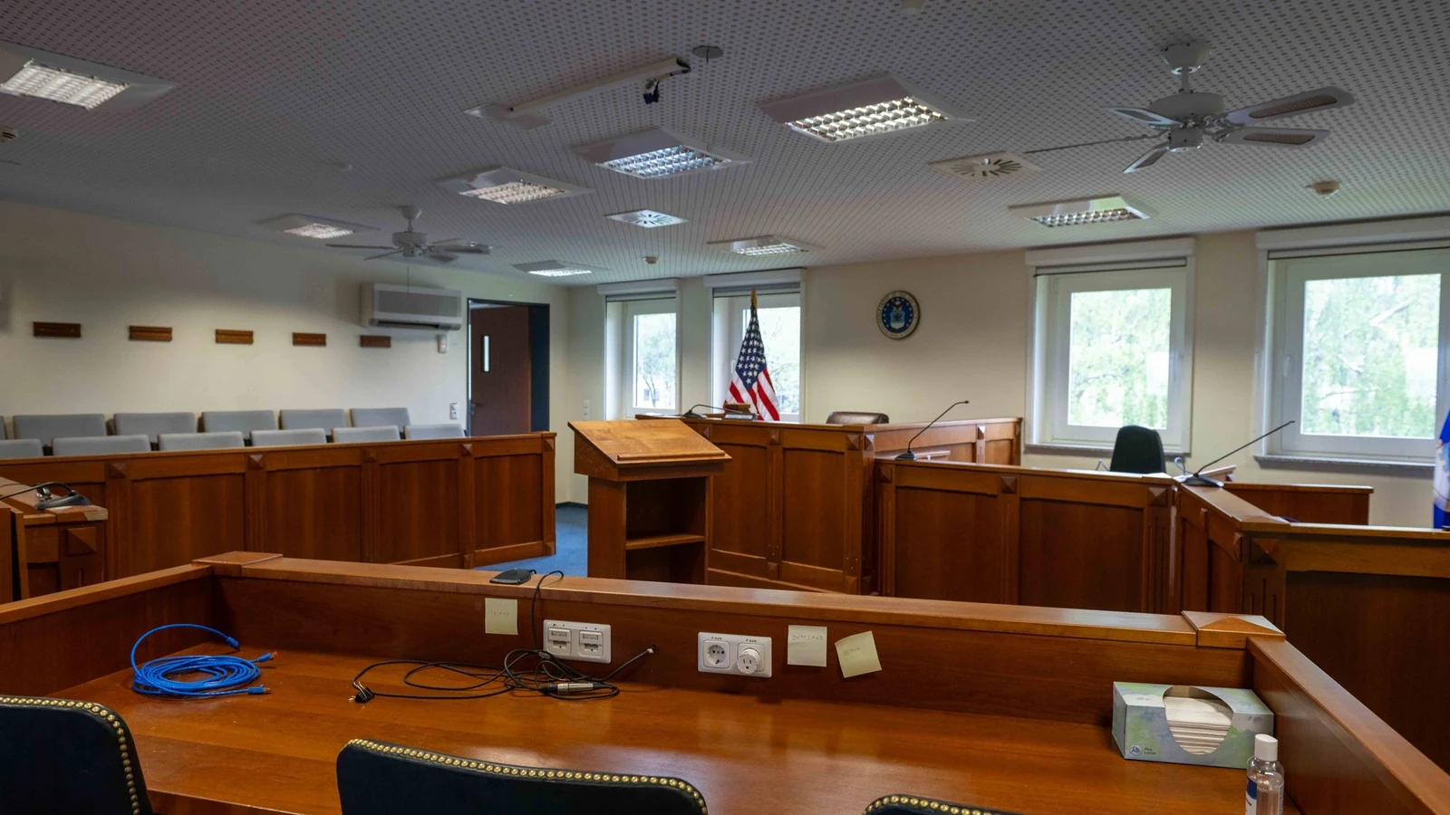 An empty trial courtroom with a judge’s bench, witness stand and counsel tables.