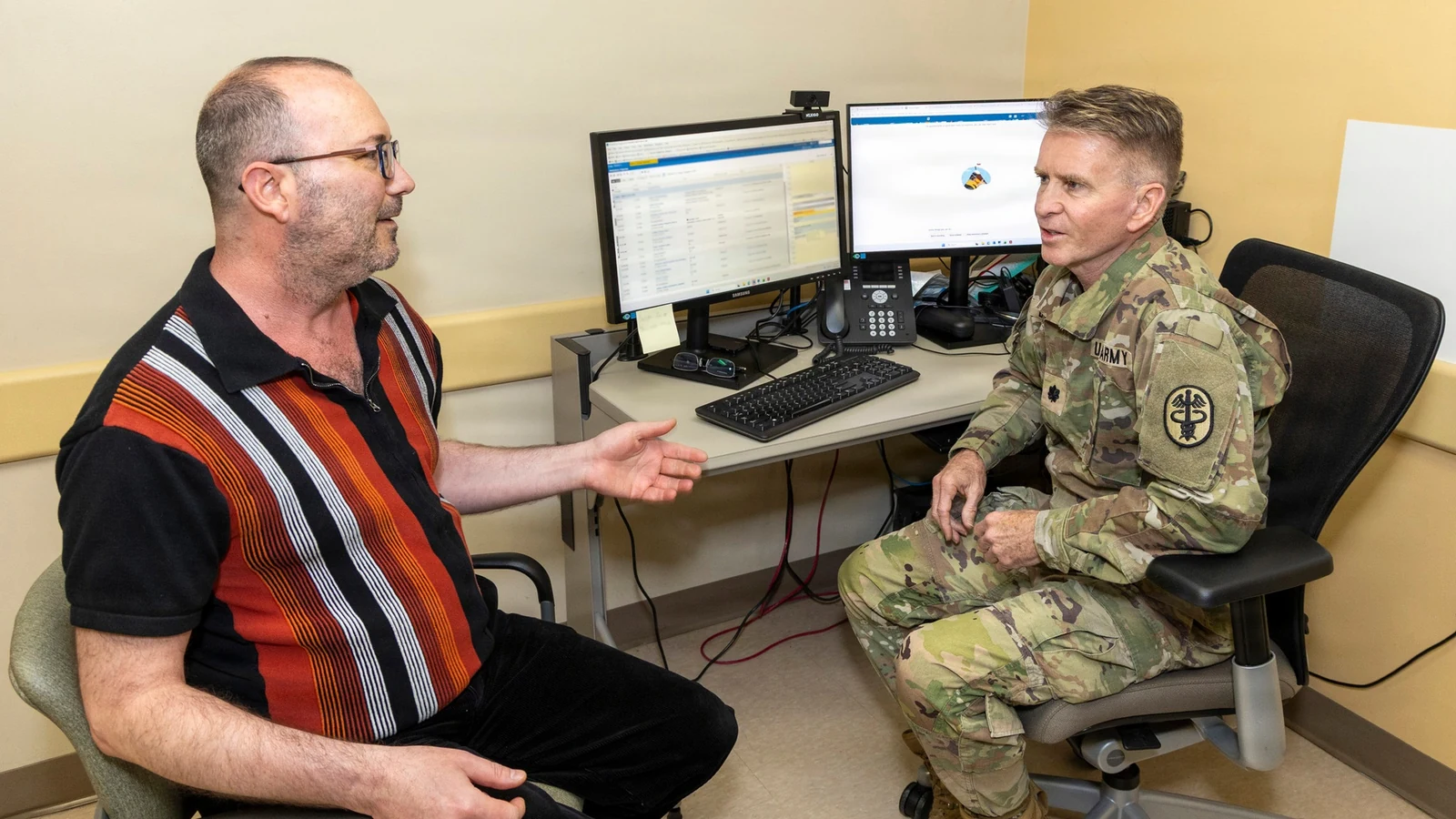 A primary-care physician speaks with a patient during an appointment while ambient-listening software operates.
