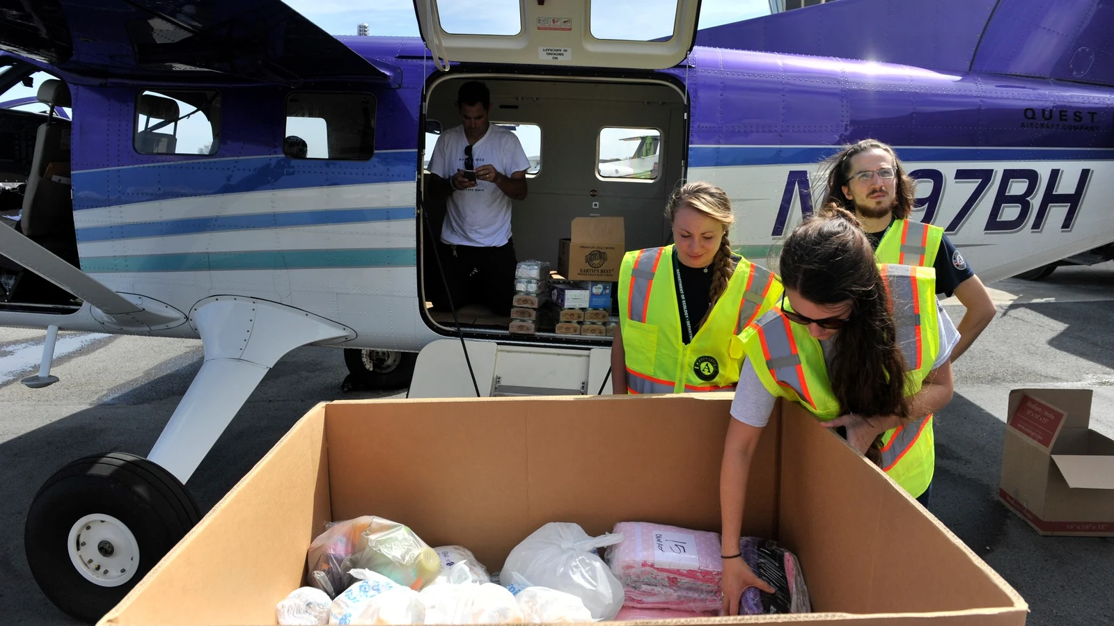 Responders and volunteers unpack pallets of infant-care supplies for storm-affected families.