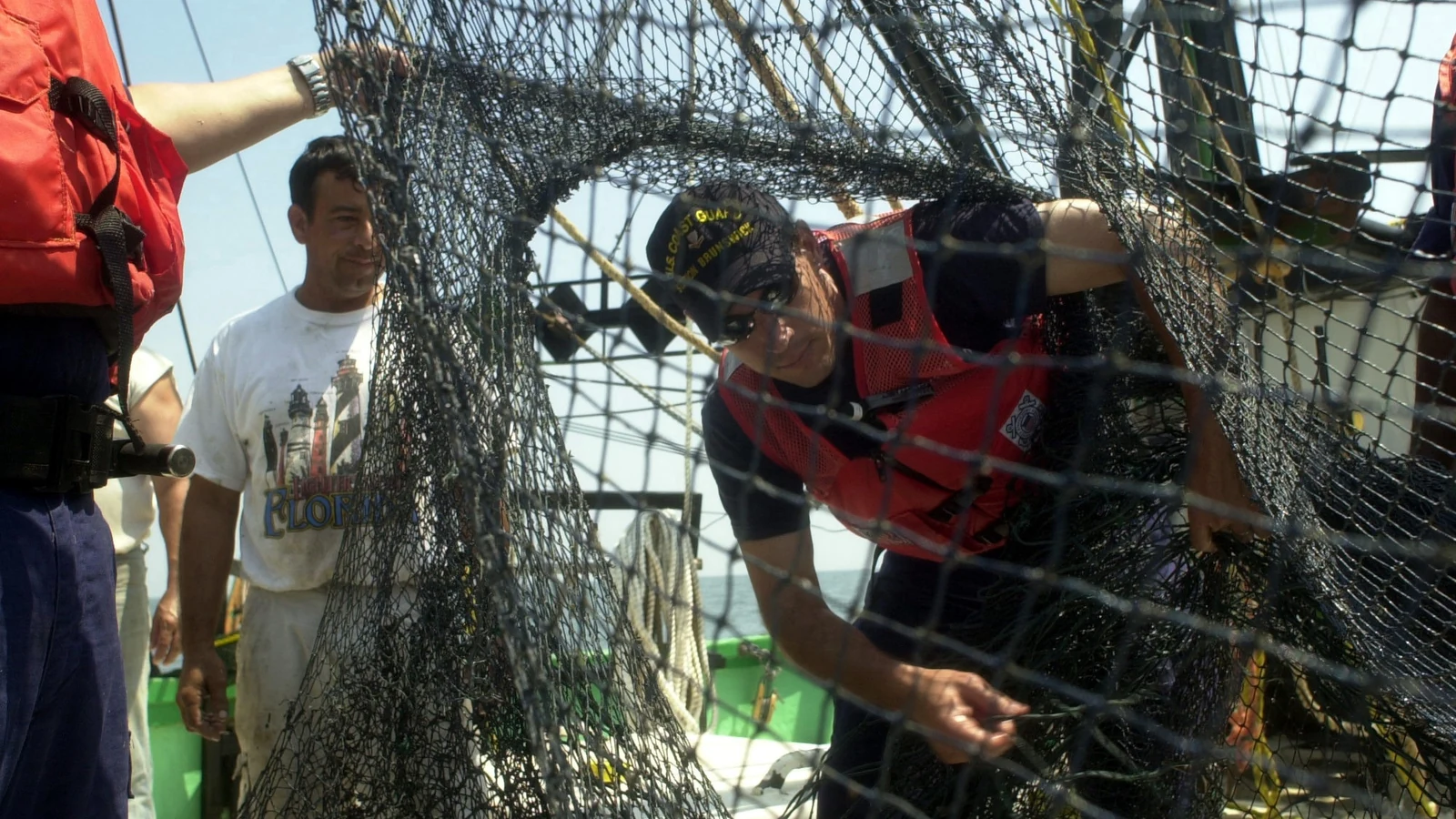 A Coast Guard officer measures a shrimp net aboard a working fishing vessel.