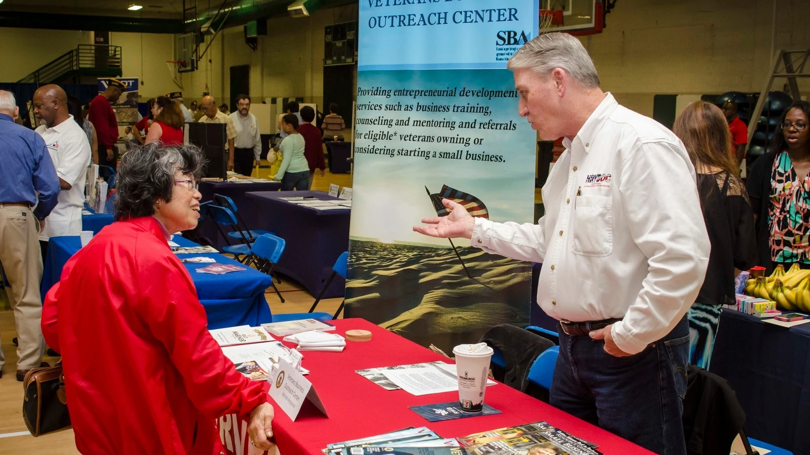 A career adviser speaks with an older veteran at a retiree summit and career fair.