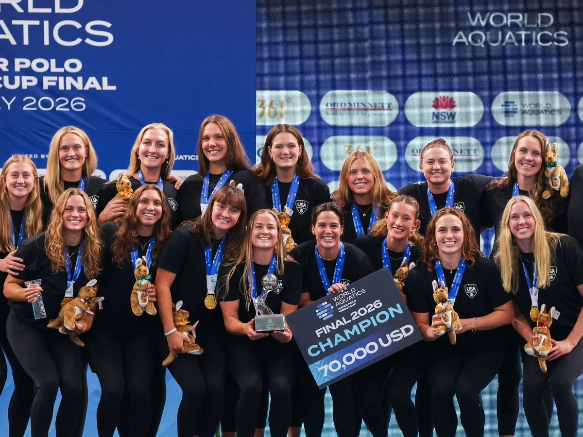 The United States women’s water-polo team poses with medals and the World Cup trophy beside the pool.