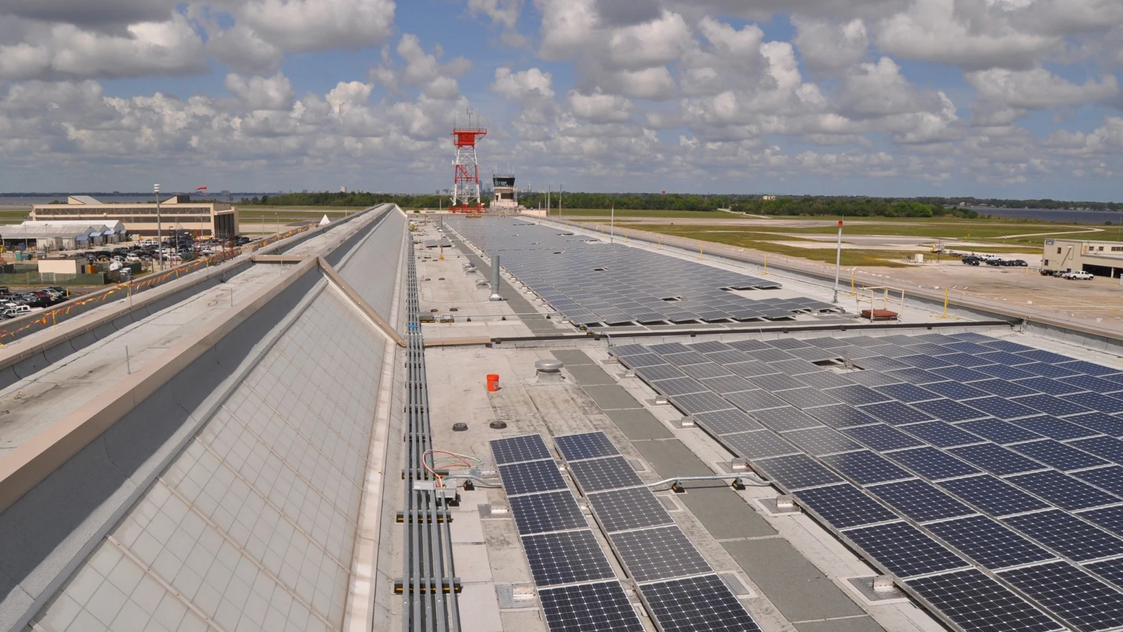 Rows of photovoltaic panels cover a large building roof.