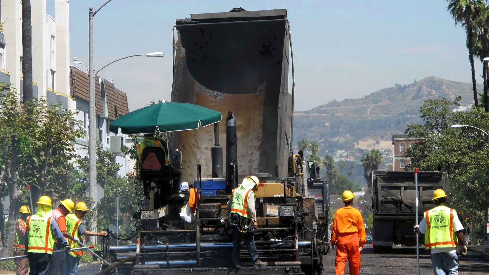 Municipal public-works crew operates paving equipment on a city street.