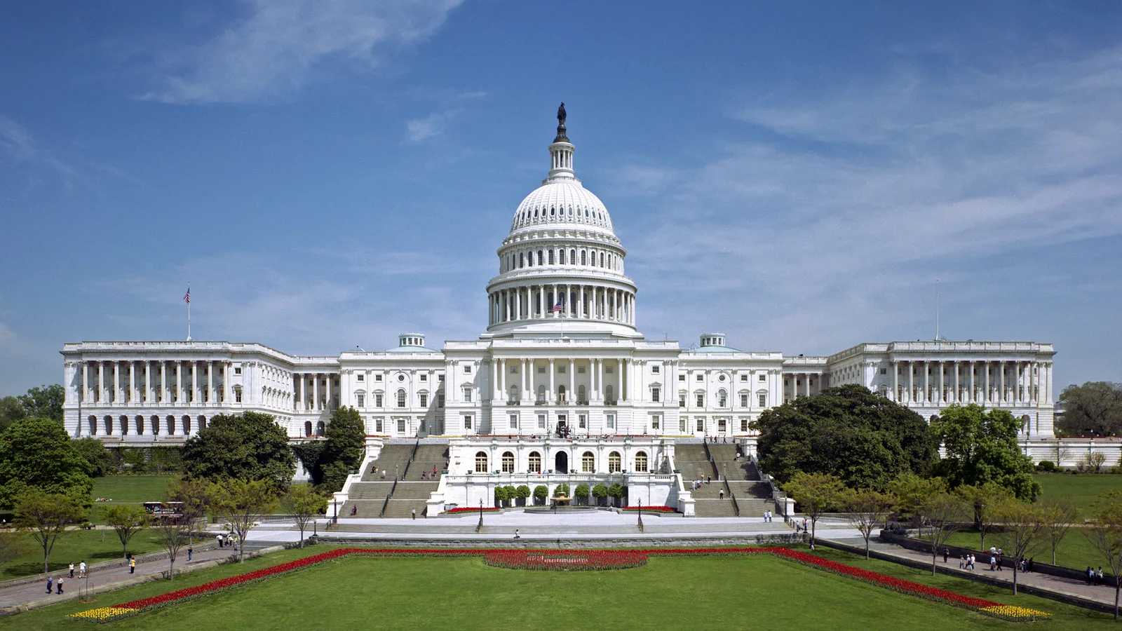 West front of the United States Capitol beneath a blue sky.