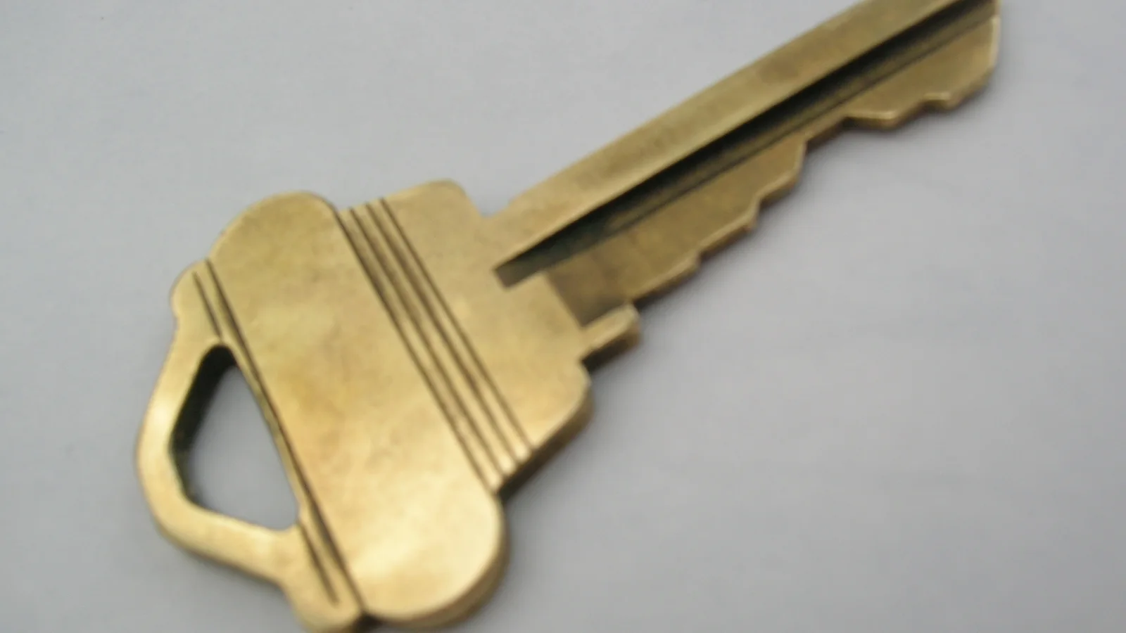 Single metal house key resting on a dark surface.