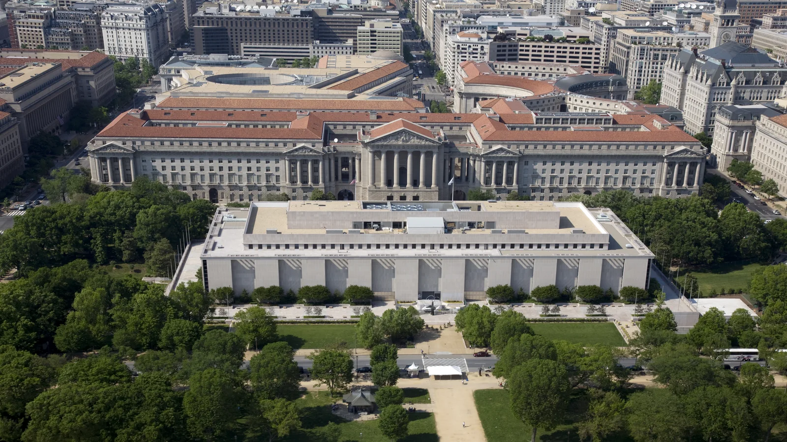 An aerial view of the rectangular National Museum of American History beside trees and federal buildings on the National Mall.