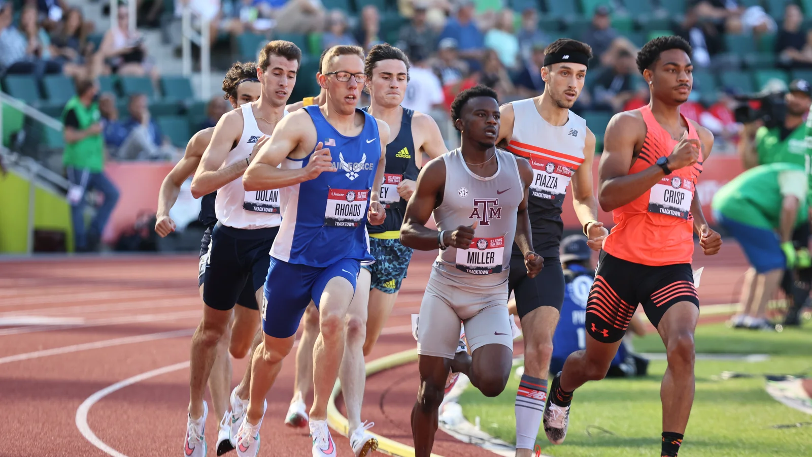 A group of middle-distance runners rounds a bend on an outdoor track during the United States Olympic trials.