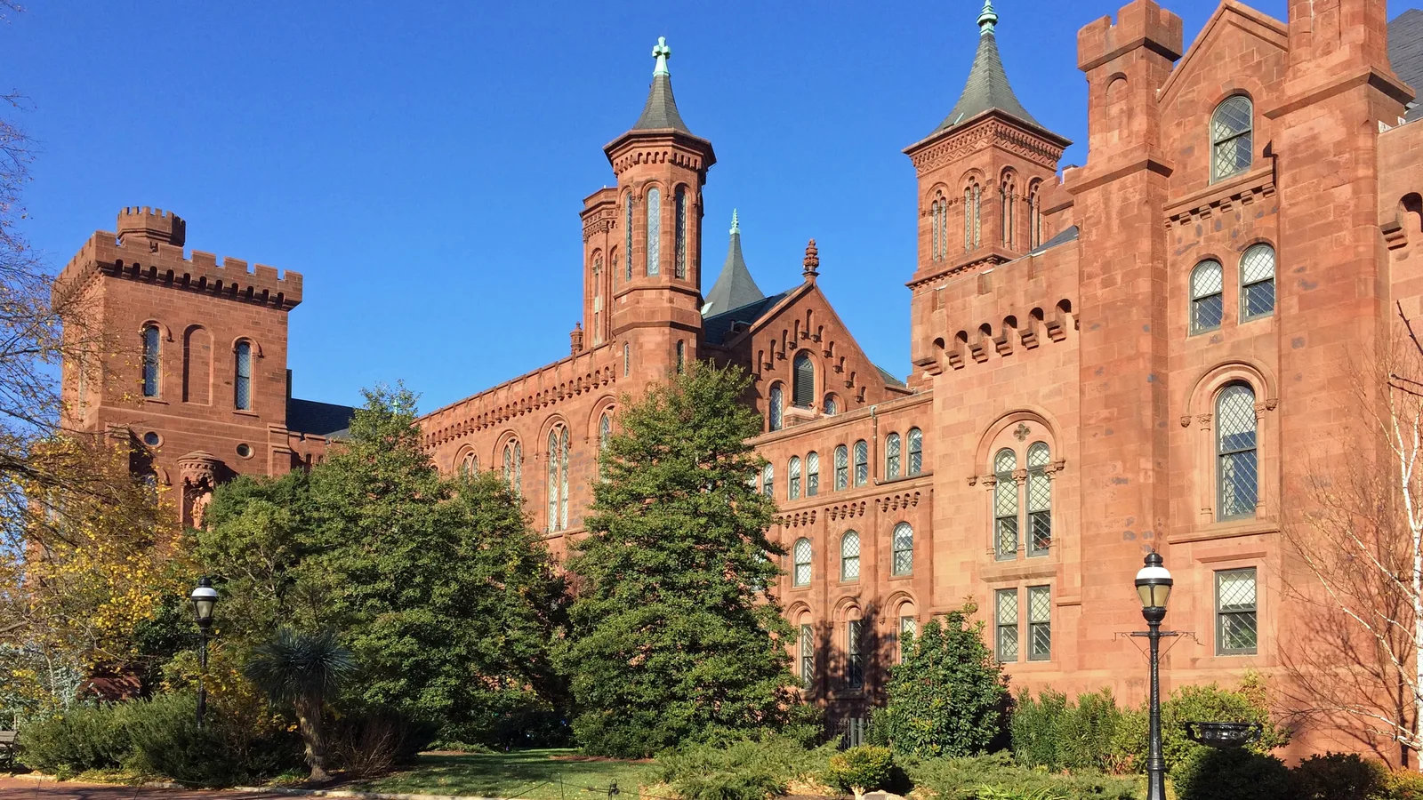The red sandstone Smithsonian Castle rises beyond a green garden in Washington.