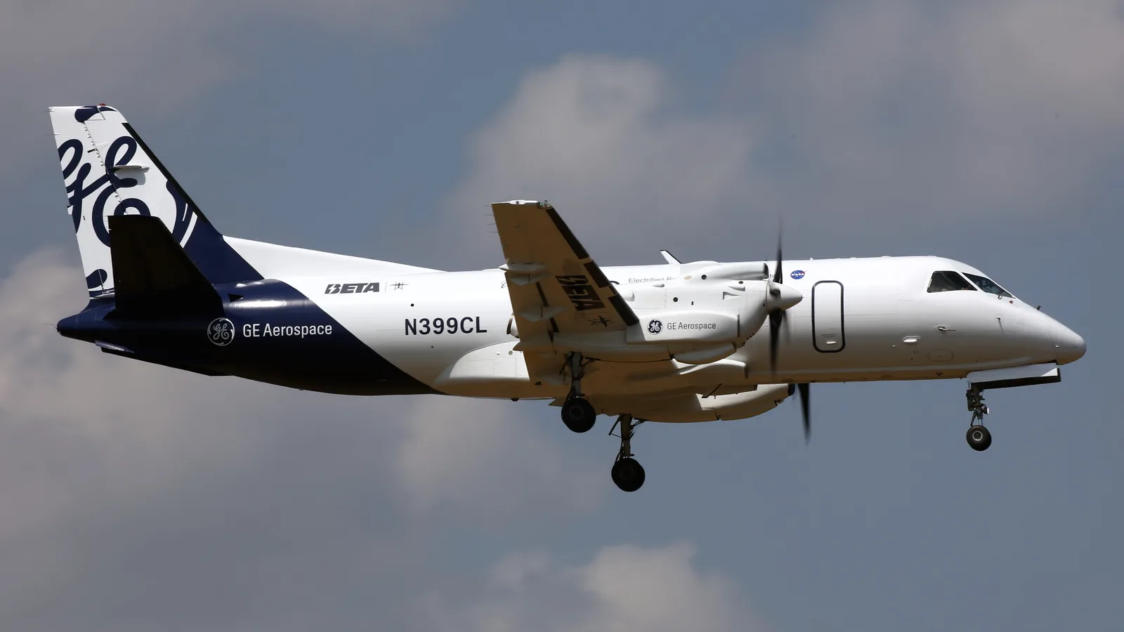 Blue and white Saab 340 aircraft flying above the runway at Farnborough.