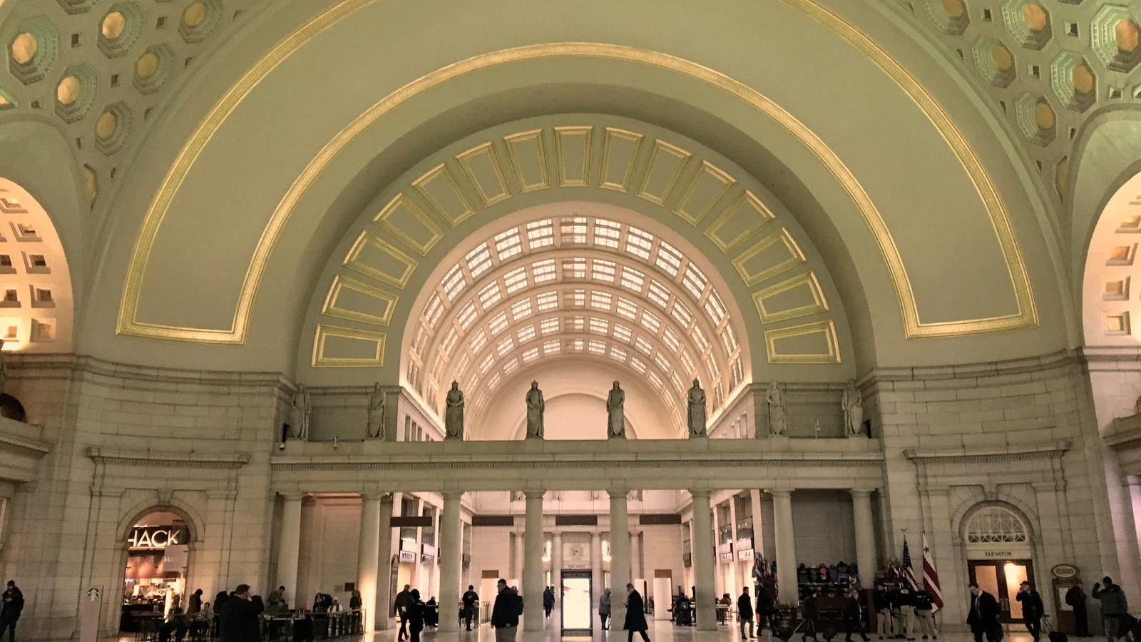 Travelers beneath the vaulted ceiling and arches of Washington Union Station.