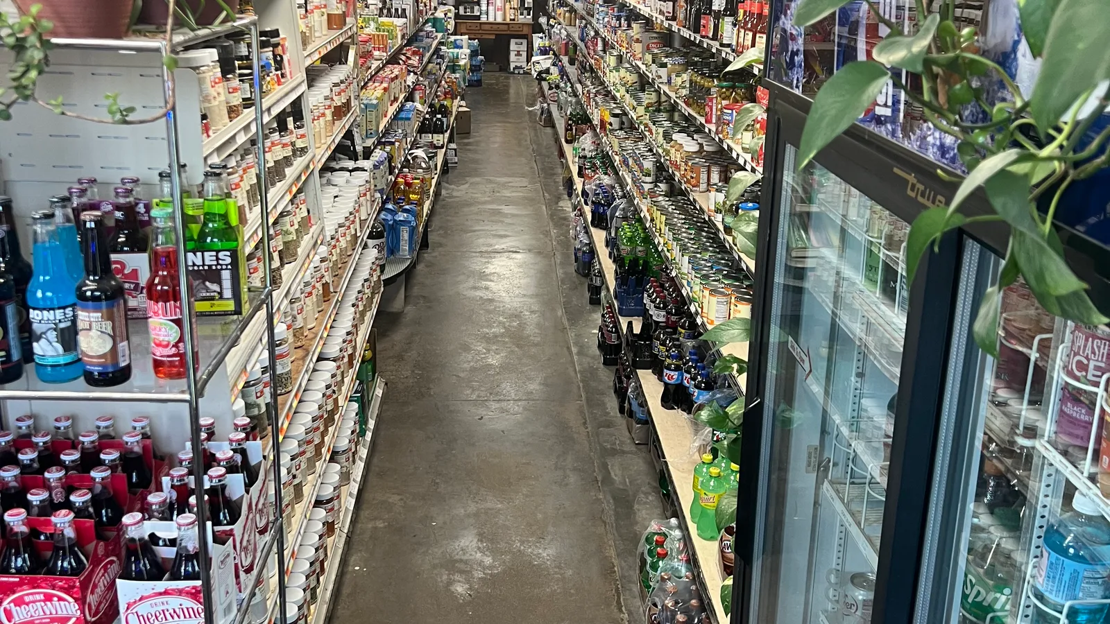 Shelves of packaged groceries extend along a brightly lit supermarket aisle.