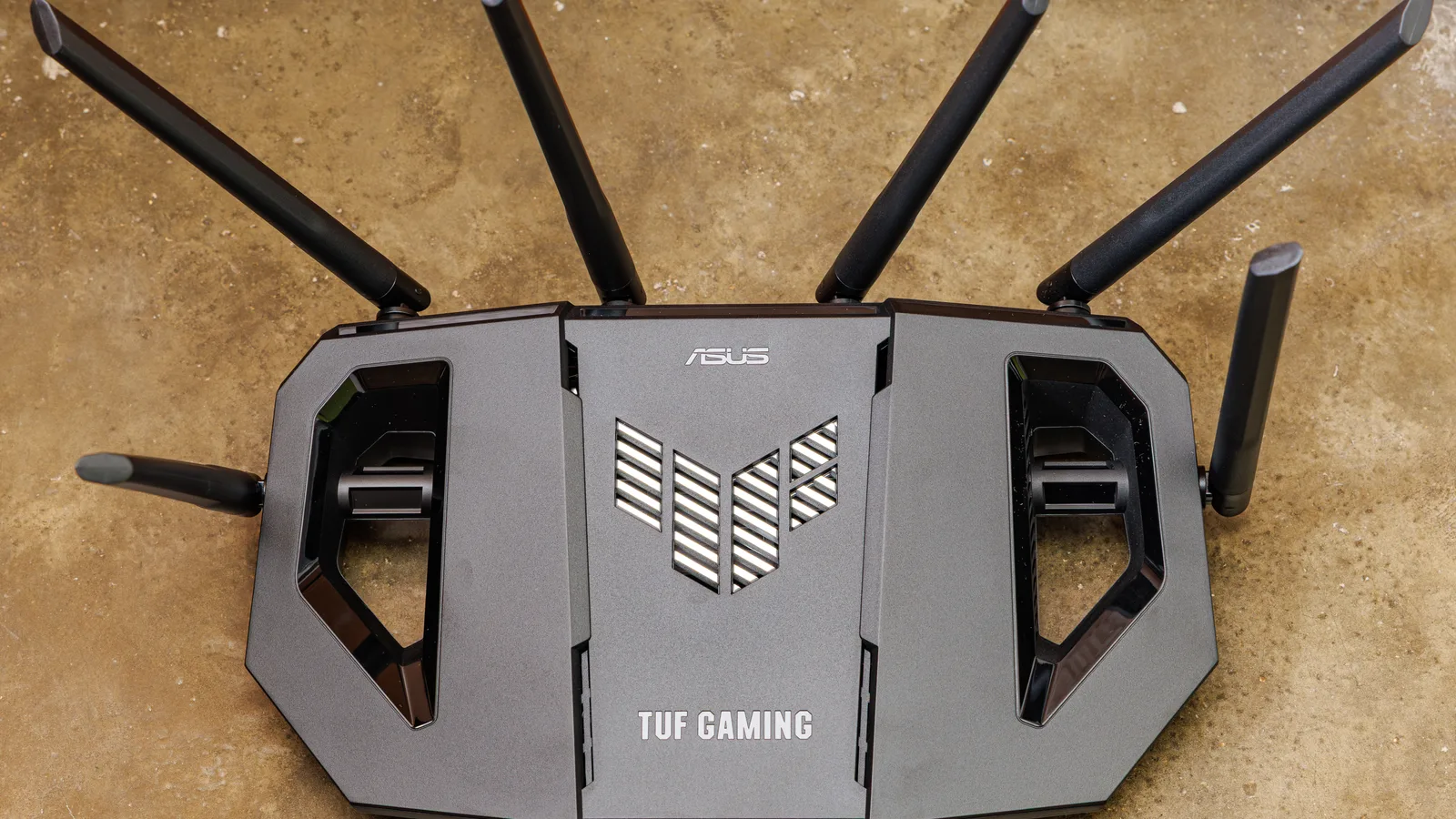A black ASUS Wi-Fi router with several upright antennas sits on a tabletop.