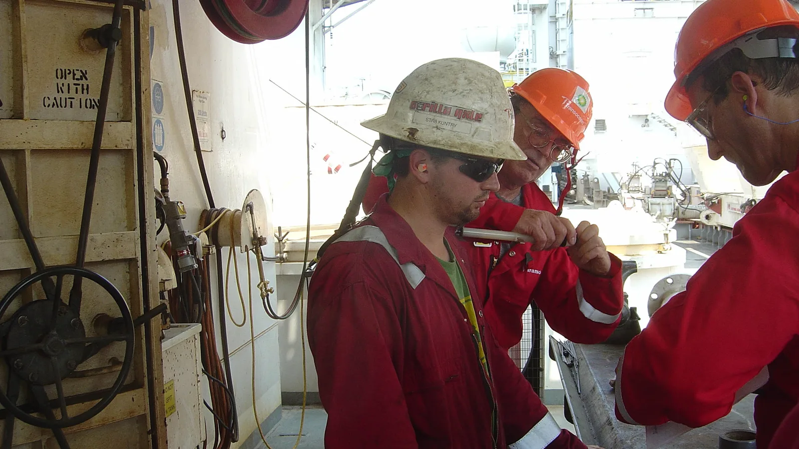 Two industrial hygienists attach air-sampling equipment near a worker's breathing zone.