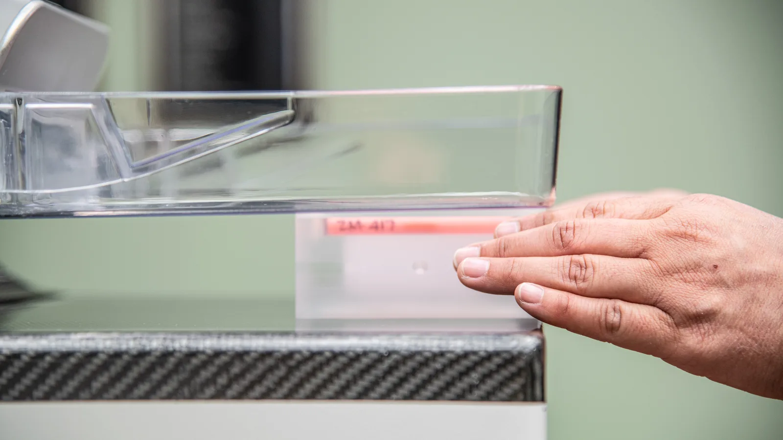 A medical imaging technician demonstrates a 3D mammography machine using a test target.