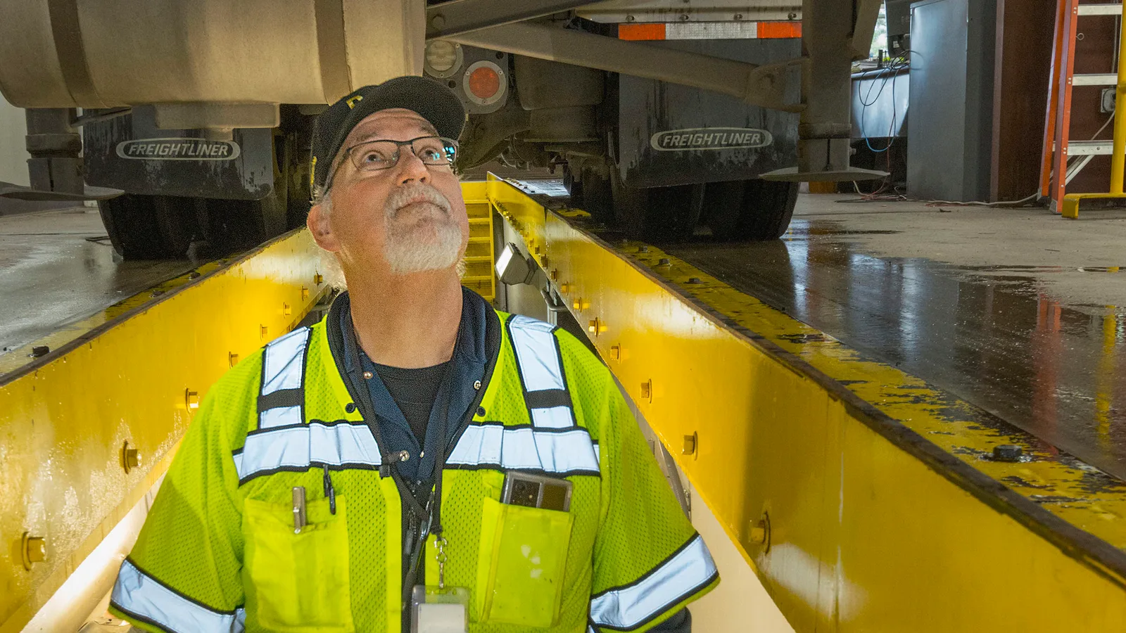 An inspector stands beside a commercial truck at a roadside inspection facility.