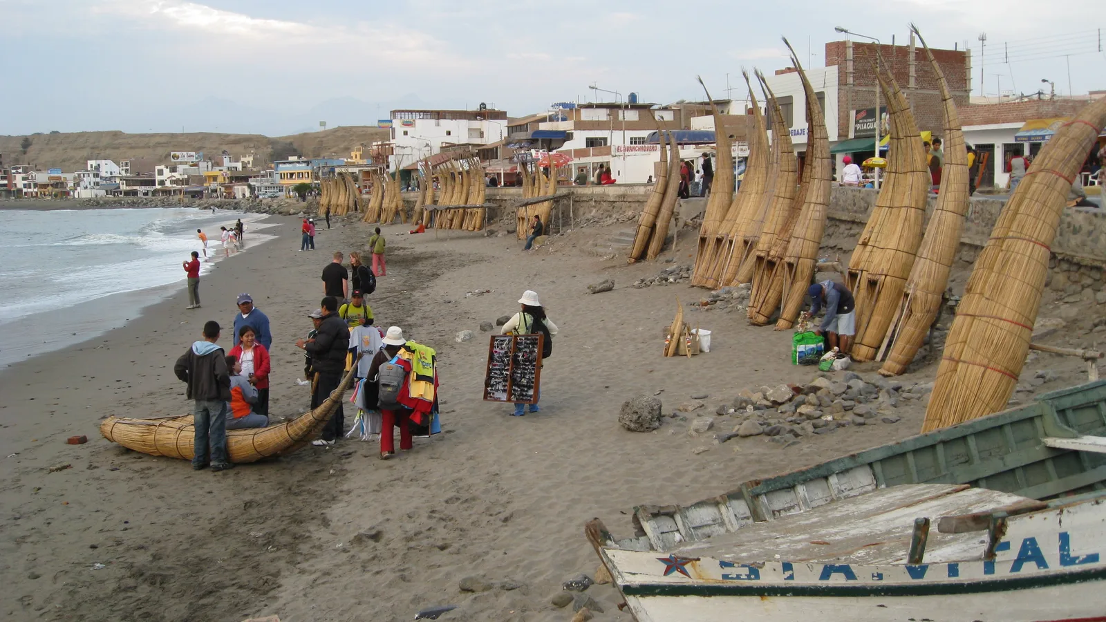 Colorful fishing boats pulled up along a sandy Peruvian shoreline.