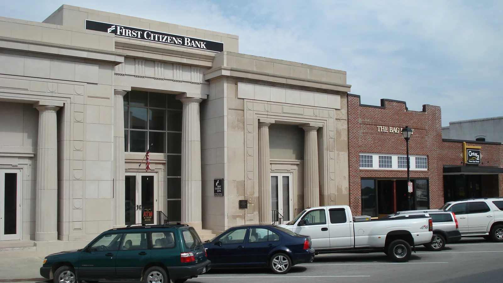Brick bank branch with columns and a drive-through under a blue sky.