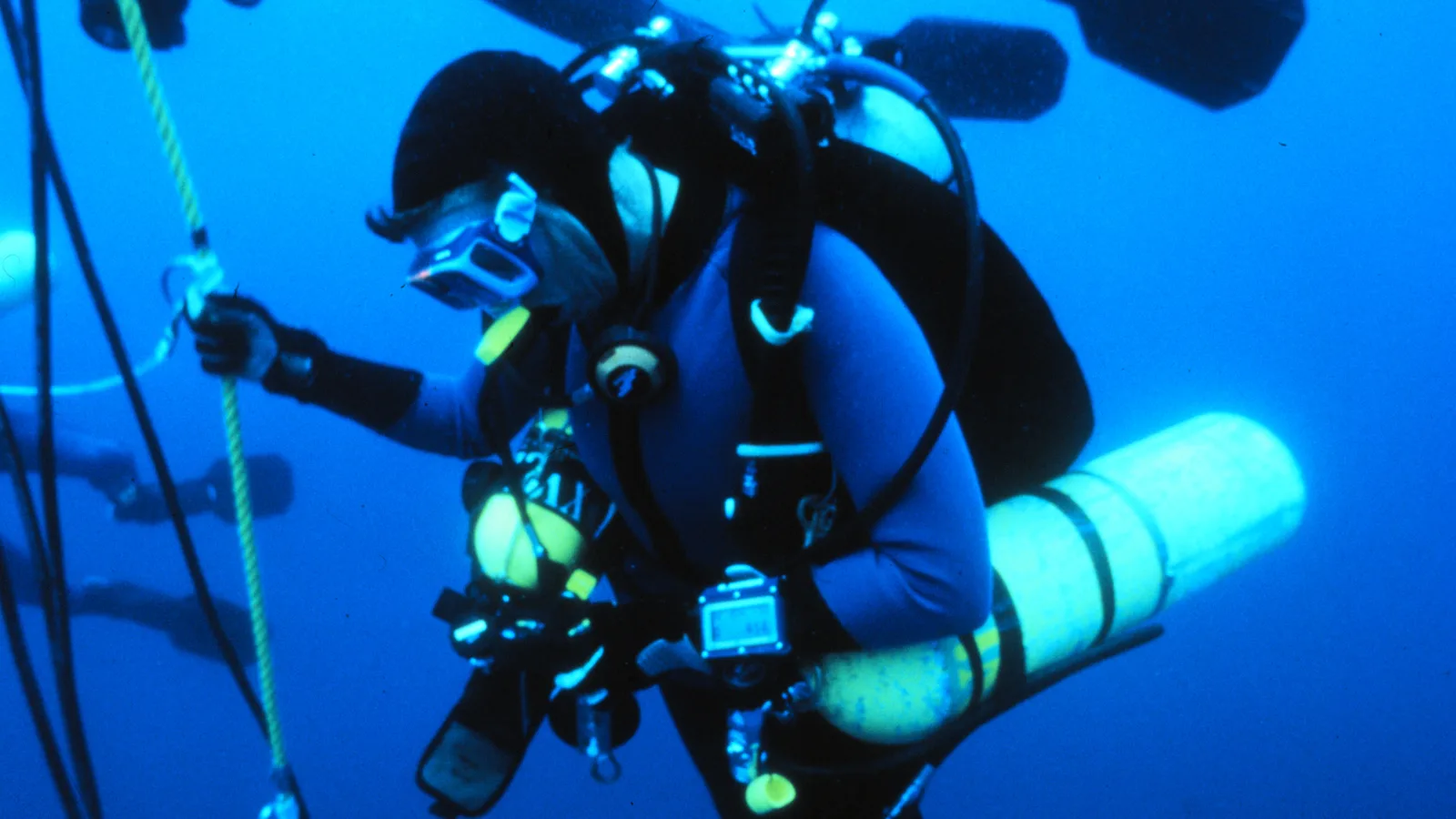 Technical diver in full equipment working underwater beside a structure.