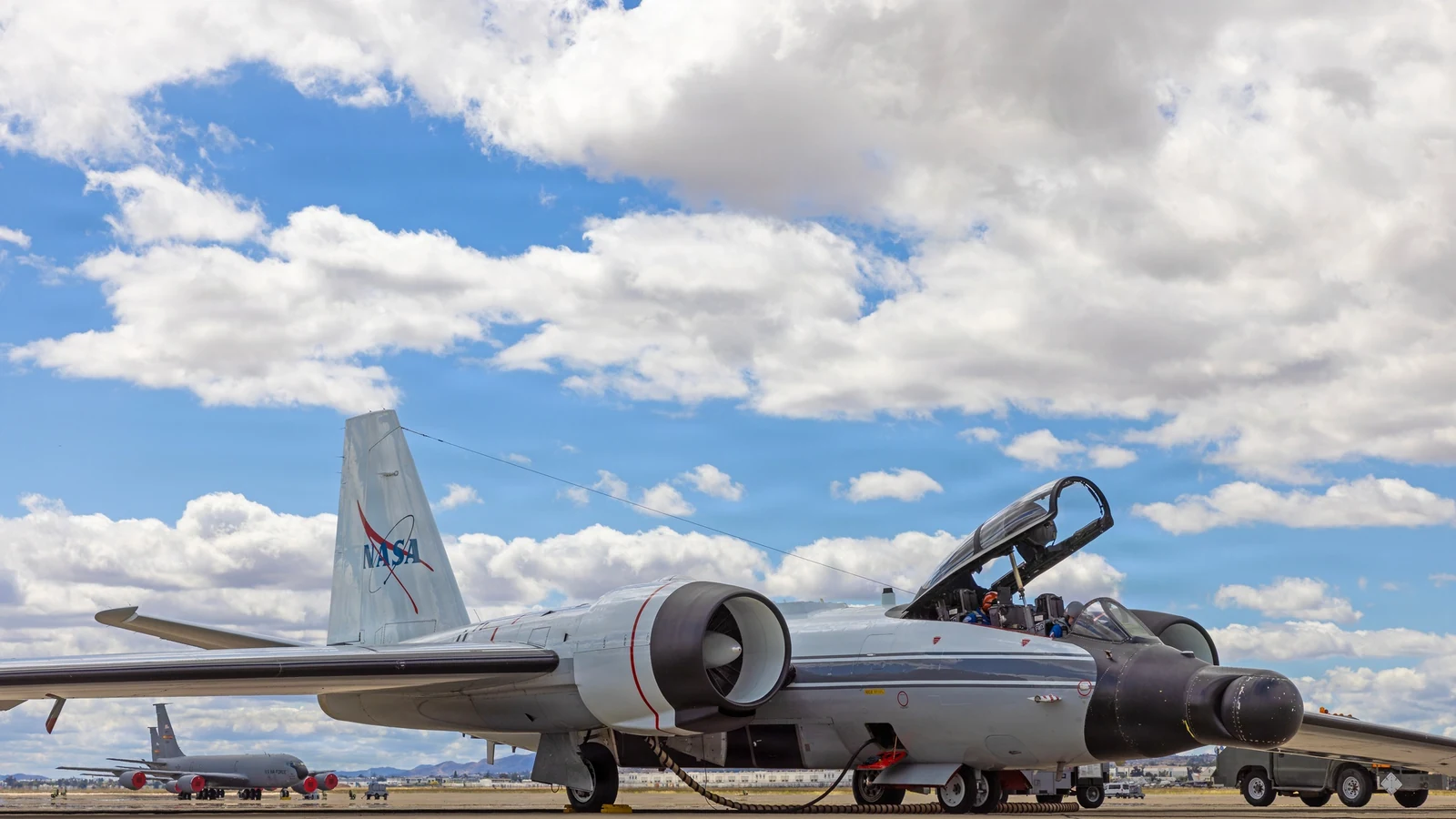 A white NASA WB-57 high-altitude research aircraft climbs into a blue sky after takeoff.