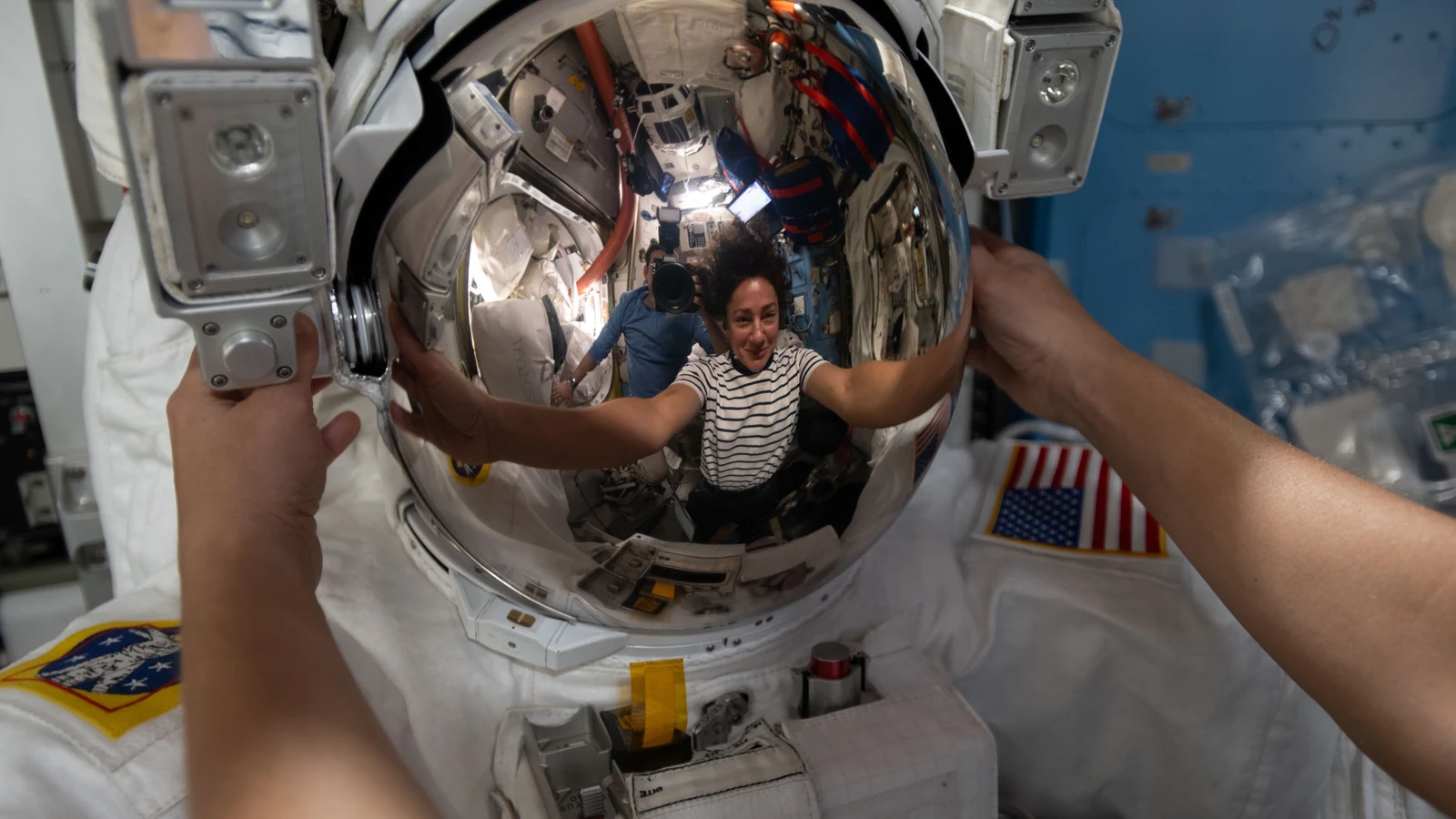 NASA astronaut Jessica Meir reflected in a spacesuit helmet inside the International Space Station's Quest airlock.