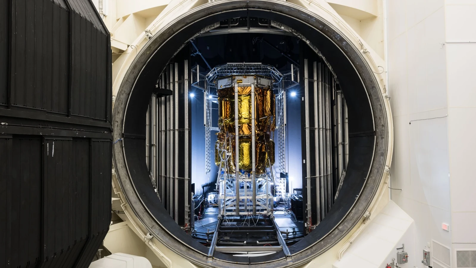 The gold-foil-wrapped Blue Moon Mark 1 lunar lander stands inside the huge circular opening of NASA Johnson’s Thermal Vacuum Chamber A.