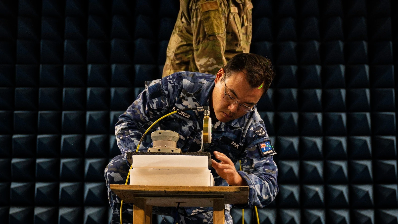 Engineers in reflective vests work around antennas and navigation equipment in a dry field.