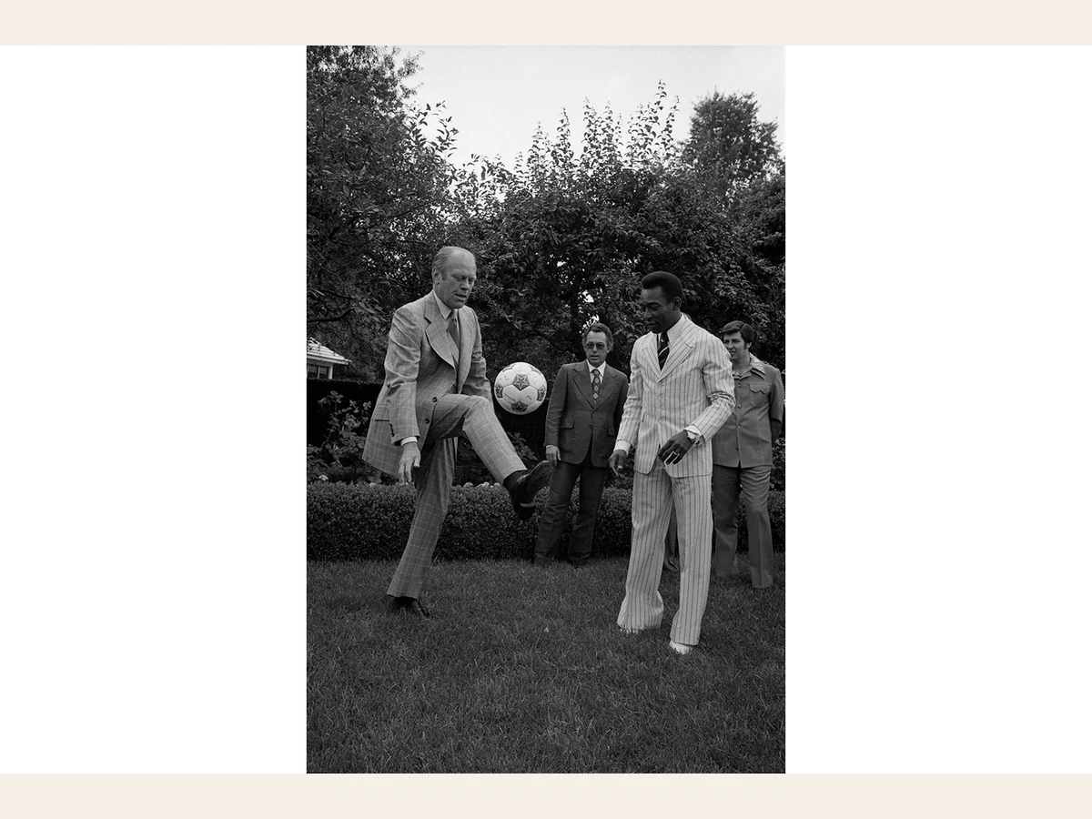 President Gerald Ford lifts a knee to juggle a soccer ball as Pelé watches in the White House Rose Garden.