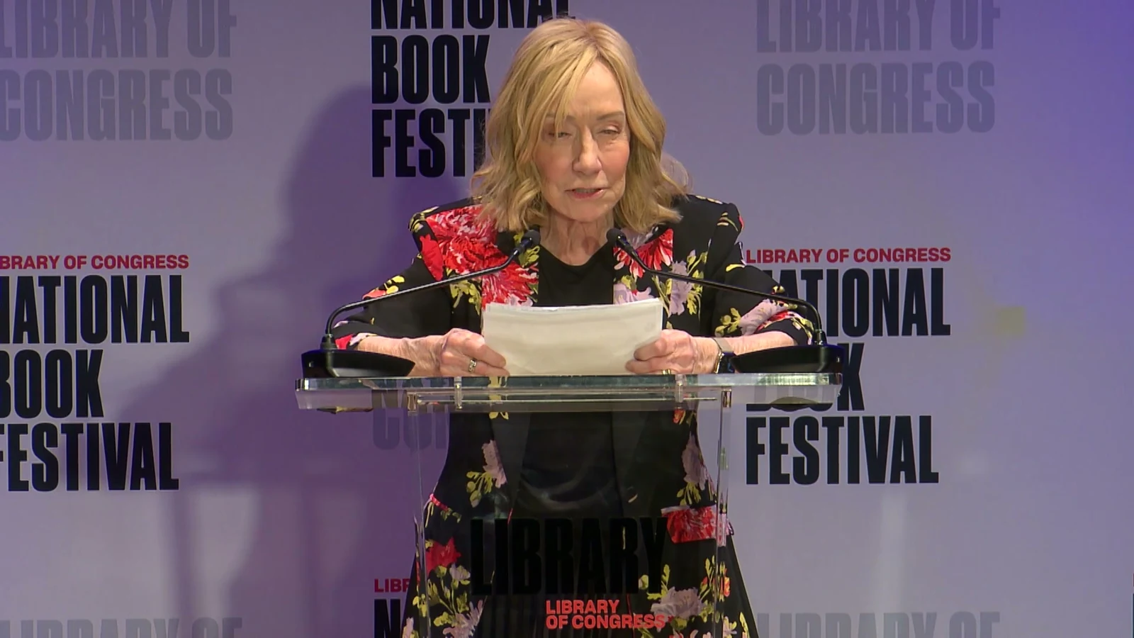 Historian Doris Kearns Goodwin reads at a clear lectern against a repeating National Book Festival backdrop.