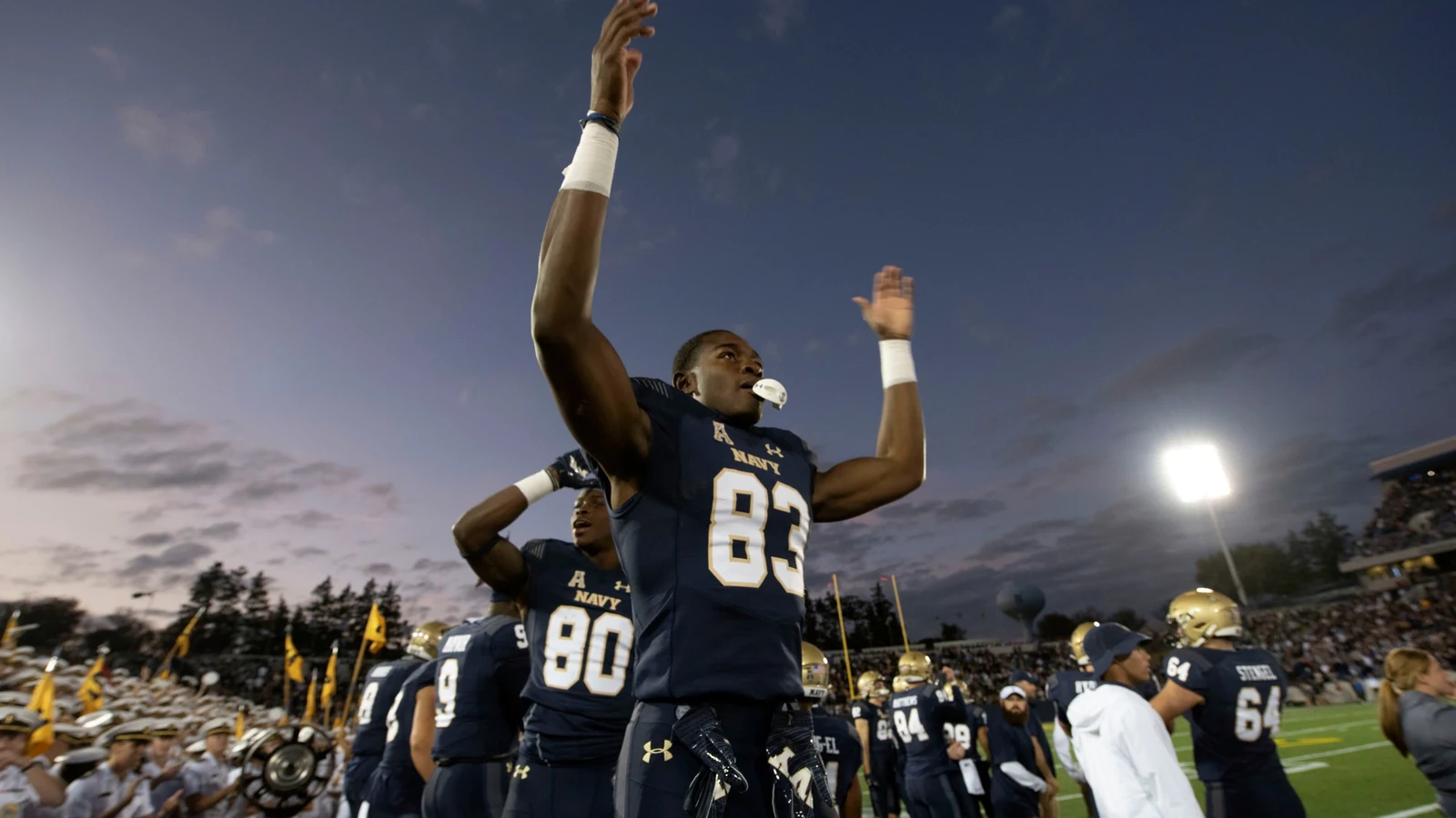 Navy football players celebrate near the sideline late in a game against Air Force.