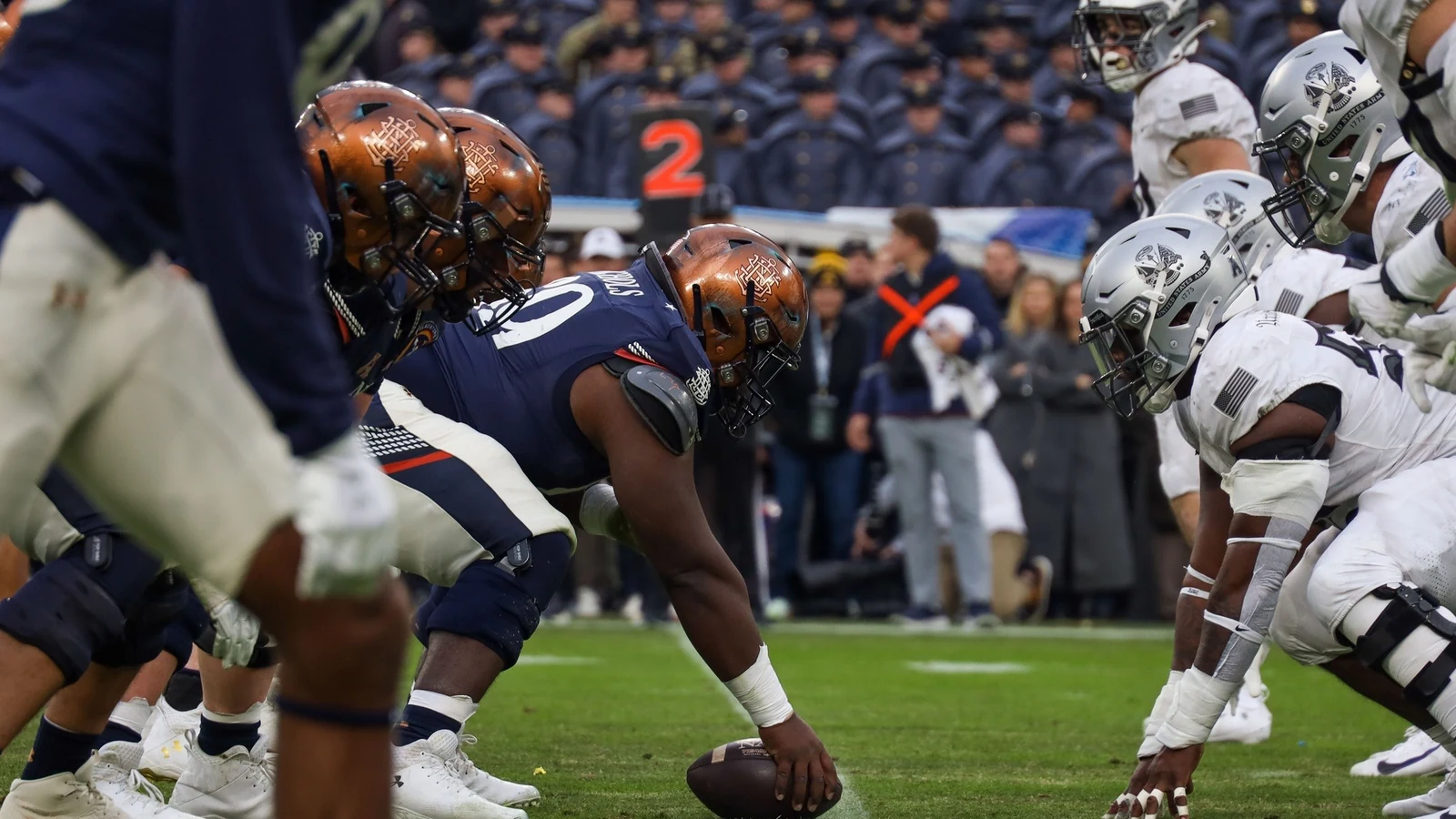 Army and Navy players line up at the line of scrimmage during a college football game.