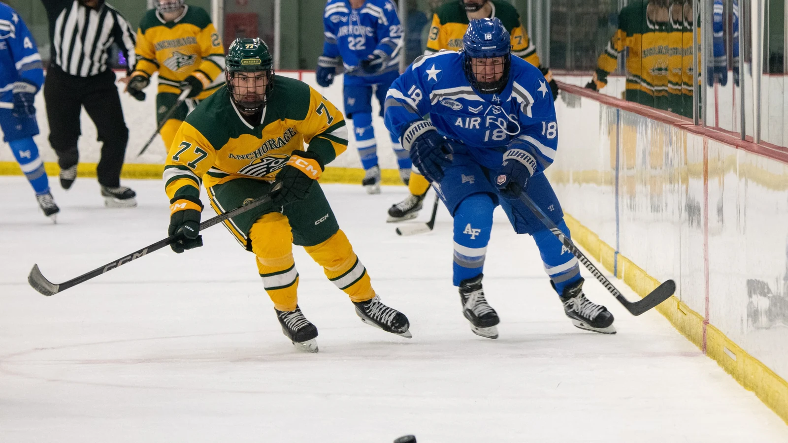 Two college hockey players race toward the puck during a game in Anchorage, Alaska.