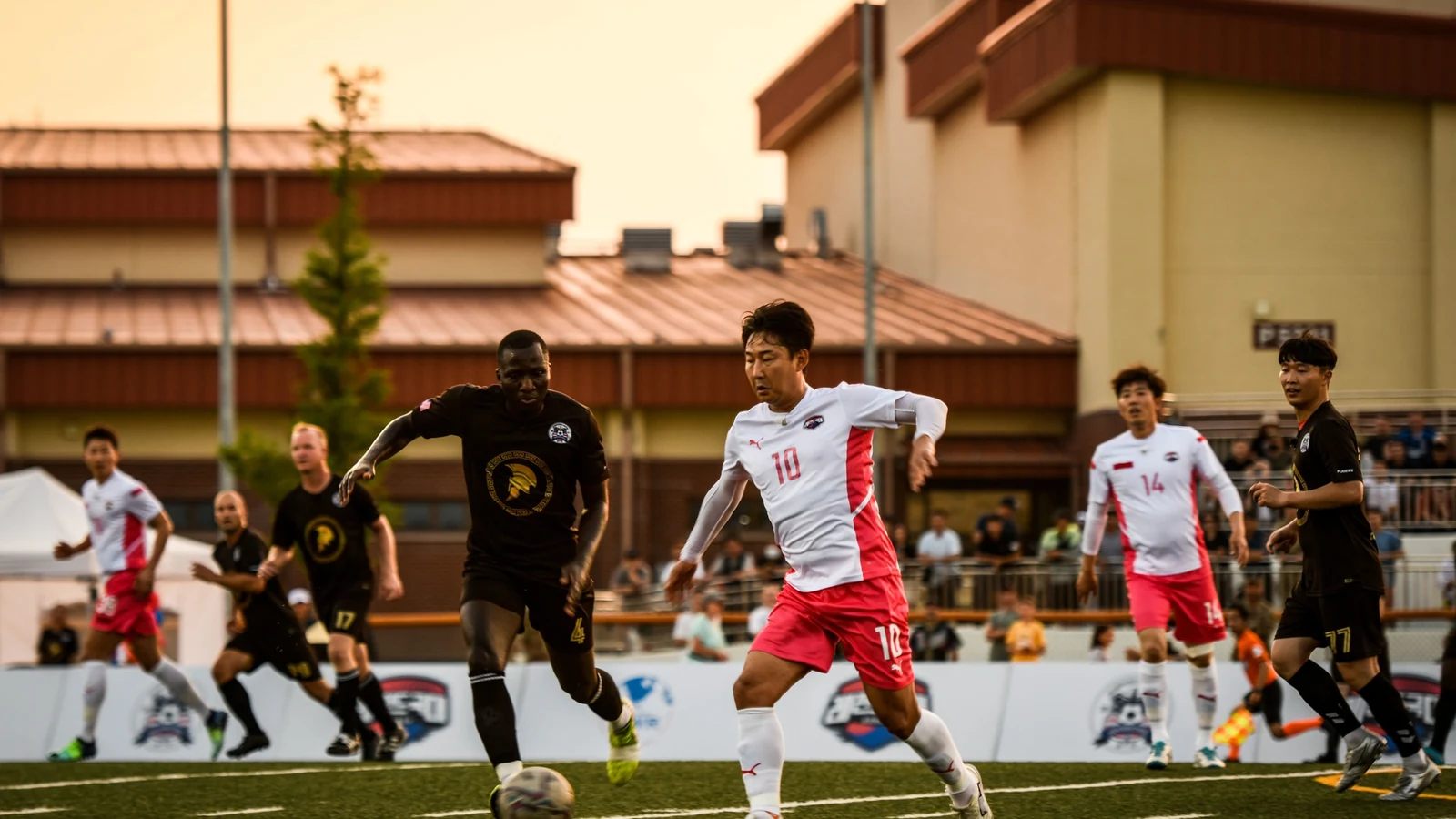 Two soccer players contest the ball during a match as teammates run behind them.