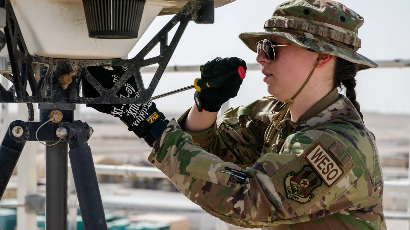 A weather technician cleans and inspects a large radar antenna inside a protective enclosure.