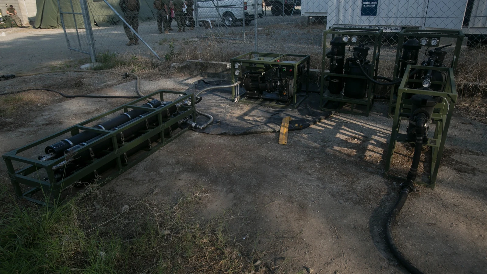 Two water specialists work beside portable purification equipment at a Papua New Guinea facility before sunrise.
