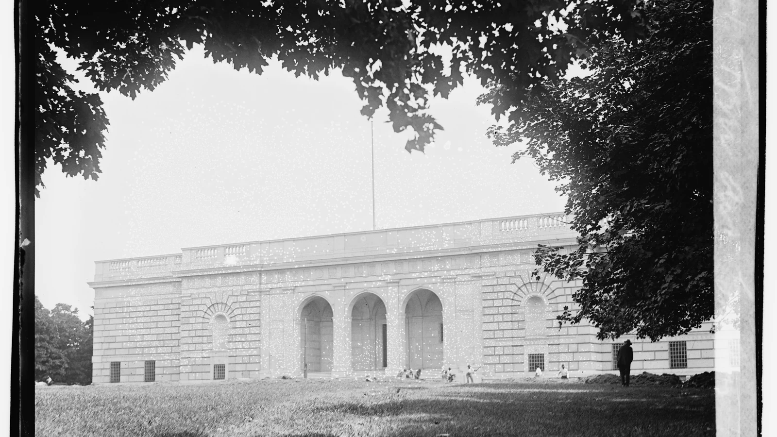 The Freer Gallery of Art’s stone facade and arched entrance stand behind trees in an early black-and-white photograph.