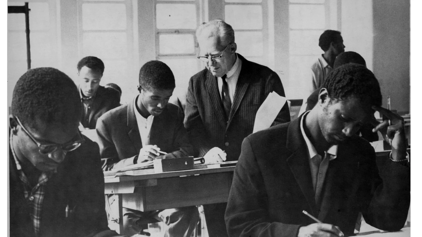 Students sit at desks and work together in a classroom.
