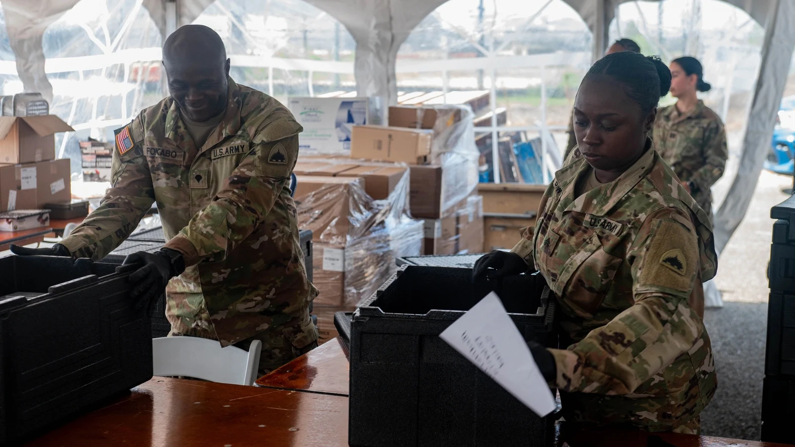 National Guard soldiers prepare rows of packaged food for distribution at Joint Base Anacostia-Bolling.