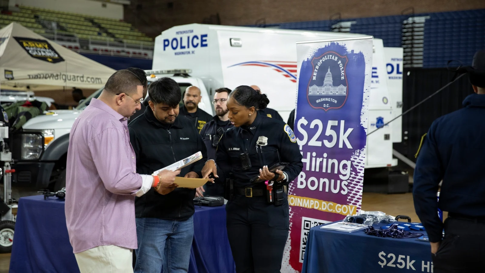 A recruiter speaks with members of the public at a job fair.