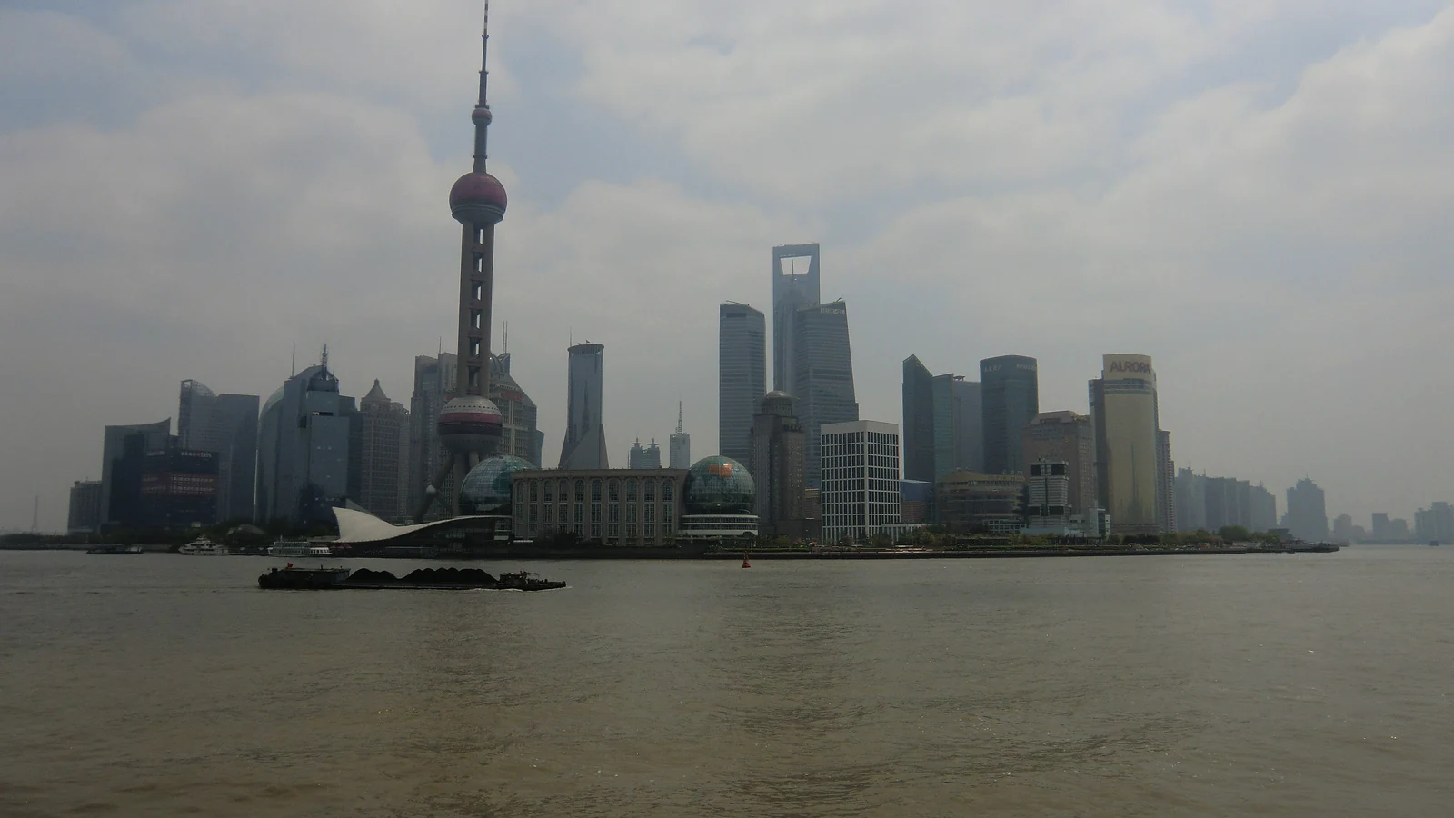 Shanghai’s central skyline rises above the Huangpu River under a pale sky.